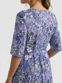 Blue and purple floral mini dress with smocked waist, angled back view.