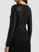 Black sequin mini dress with long sleeves and tiered fringe skirt, back angled view.