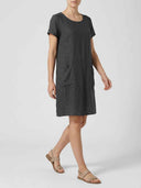 Charcoal linen mini dress with short sleeves and pockets, angled side view on a white background.