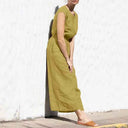 Olive green cotton-linen jumpsuit with relaxed crew neck, angled view against a white wall.