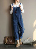 Navy blue velvet wide-leg overalls with front pockets, worn over a white long-sleeve shirt, front view.