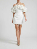White off-shoulder mini dress with voluminous ruffled sleeves, front view on a light background.