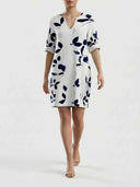White V-neck mini dress with navy leaf print, cuffed sleeves, front view on a white background.