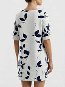 White mini dress with dark blue leaf pattern, rolled sleeves, back view.