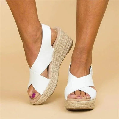 White cross-strap espadrille wedge sandal with braided jute rope sole and slingback buckle, peep-toe front view on neutral background.