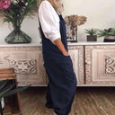 Navy blue jumpsuit with pockets over a white shirt, side view.