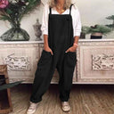 Black jumpsuit with front pockets, worn over a white long-sleeve shirt, front view.