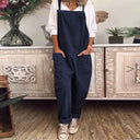 Navy blue jumpsuit with front pockets, worn over a white shirt, front view.