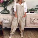 Beige jumpsuit with knotted straps and large pockets, worn over a white shirt, front view.