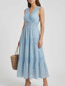 Light blue maxi dress with gold and white polka dots, lace trim, and a straw bag, front view.