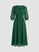 Green V-neck mini dress with sheer long sleeves and ruched waist, front view on white background.