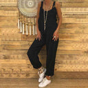 Black denim overall with spaghetti straps and loose fit, front view on wood background.