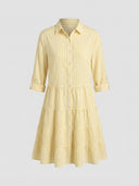 Yellow and white striped tiered mini dress with rolled sleeves, front view on gray background.