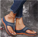 Navy blue rhinestone flatform sandals with bow crystal detail and orange contrast sole, worn with distressed jeans, cushioned thong sandal angled view.