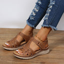 Brown flatform sandals with woven strappy upper and cushioned sole, angled front view on wooden surface.