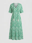 Green and white ikat print maxi dress with V-neck, short sleeves, and tassels, front view.