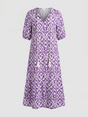 Purple and white ikat print maxi dress with V-neck and tassel ties, front view on gray background.