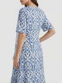 Blue and white ikat print maxi dress with short sleeves and tassels, angled back view.