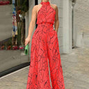 Red halter jumpsuit with black abstract print, wide legs, and pockets, front view.