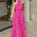 Pink halter jumpsuit with black abstract face print, front view.