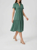 Green polka dot midi dress with collar, short sleeves, and tiered skirt, angled view.