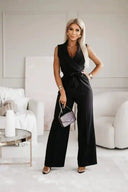 Black sleeveless jumpsuit with wide legs, V-neck, and waist tie, front view.