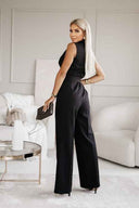 Black sleeveless jumpsuit with wide legs, back angled view in a living room.