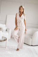 Light pink sleeveless jumpsuit with V-neck and waist tie, front view.