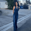 Dark wash denim jumpsuit with low-cut neckline, front zipper, and flared legs, full front view.