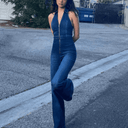 Dark wash denim jumpsuit with low-cut neckline and front zipper, angled full view.