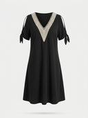 Black V-neck knee-length dress with cream crochet trim and tie sleeves, front view on white background.