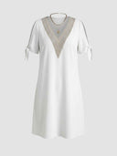 White V-neck dress with gold lace trim, tie sleeves, and gold necklaces, front view.