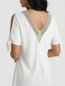 White dress with V-neck lace trim, tie sleeves, and back zipper, shown from the back.