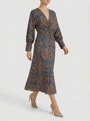 Blue maxi dress with brown floral print, V-neck, and twisted front, angled view.
