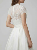 White midi dress with lace bodice, high neck, cap sleeves, and pleated skirt, angled back view.