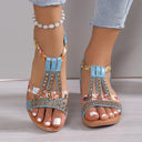 Blue embellished flatform sandals with multicolour rhinestone cage straps and floral-print fabric panels, open-toe style, angled front view.