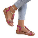 Pink embellished flatform sandals with rhinestone and sequin-detail cage straps, open-toe T-bar style, angled side view on model wearing jeans.