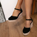 Black closed-toe espadrille wedge sandals with natural jute rope wedge sole and adjustable ankle strap, angled three-quarter view.