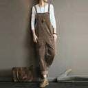 Brown corduroy jumpsuit with large front pockets, worn over a white long-sleeve shirt, front view.