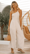 Beige sleeveless jumpsuit with cinched waist, one shoulder strap, and wide legs, front view.
