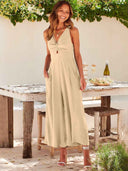 Beige wide-leg overall with V-neck and front cutout, standing outdoors, front view.