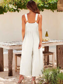 White wide-leg overall with gold ring straps and smocked bodice, back view.