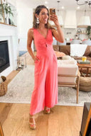 Coral wide-leg jumpsuit with knotted bodice and cutout, front view in living room.