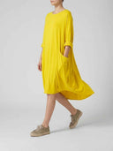 Yellow mini shirt dress with pockets, side view on a light gray background.