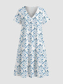 White mini dress with blue leaf print, V-neck, and tiered skirt, front view.