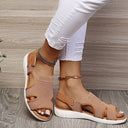 Khaki mesh low wedge sandals with white cushioned sole, open toe and velcro slingback strap, worn with white distressed jeans, angled side view.