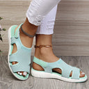 Mint green mesh low wedge sandals with white cushioned sole, cutout side panels and open toe, angled front view worn with white distressed jeans.