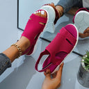 Fuchsia mesh low wedge sandals with white cushioned sole, cutout upper and velcro slingback strap, angled view on feet.