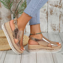 Gold metallic platform wedge sandals with woven espadrille rope sole, broad cross-strap toe band and buckle ankle strap, angled front view.