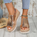 Gold metallic platform sandals with chunky woven sole and ankle strap buckle closure, front three-quarter view on white wooden background.